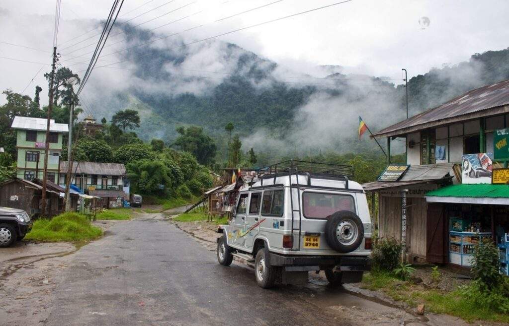  Image of a traditional Sikkimese house in Yuksom surrounded by mountains and greenery.