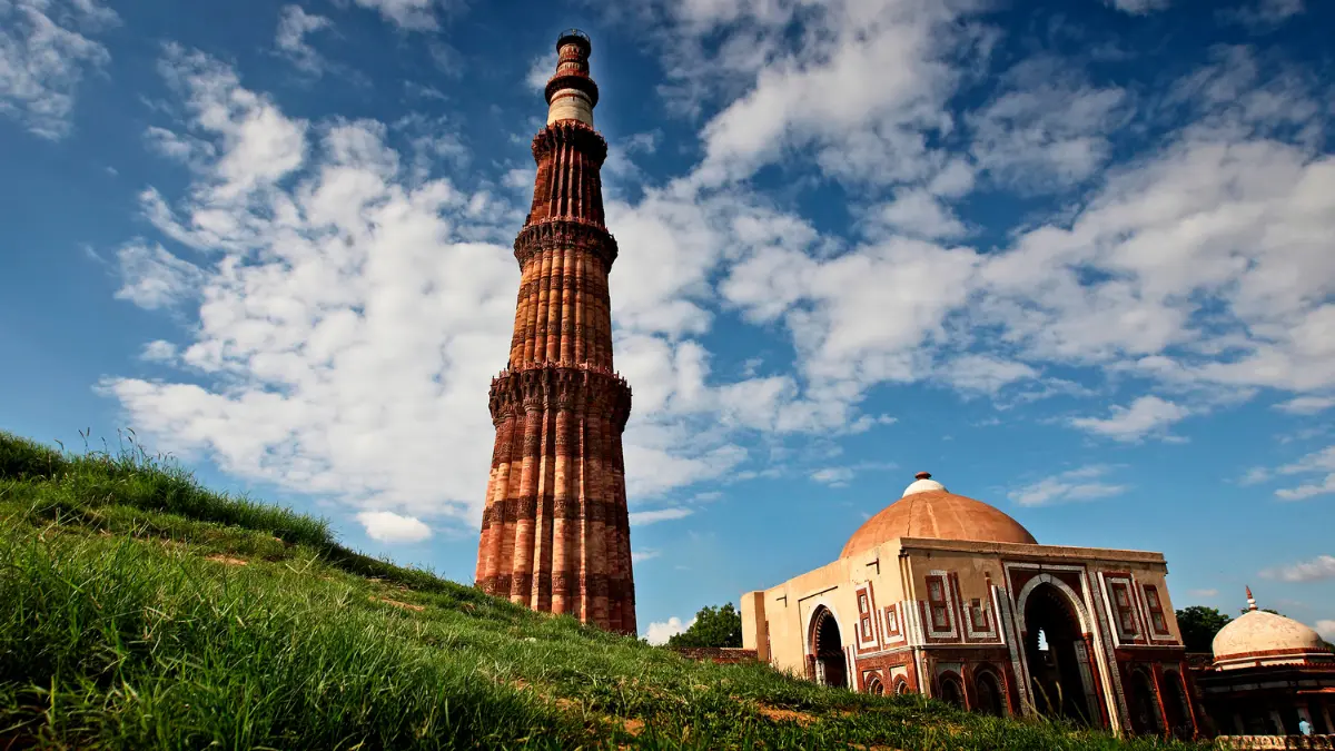 A photo of the Qutub Minar, a tall minaret made of red sandstone and marble. The minaret is located in Delhi, India.