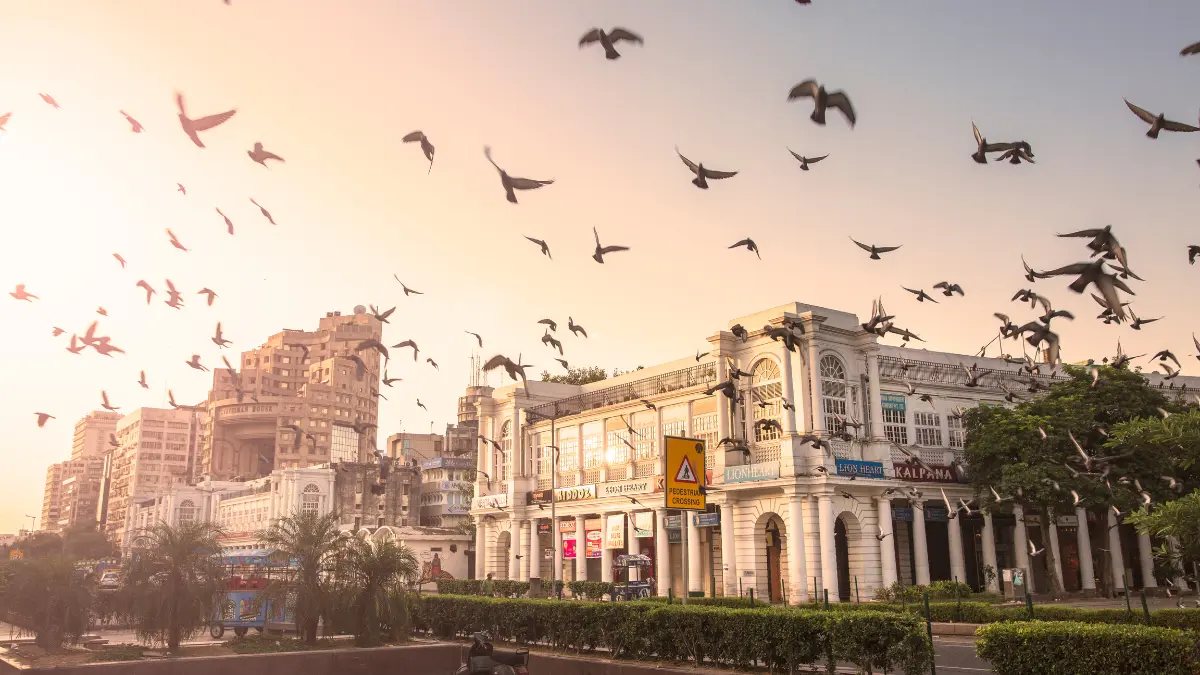 A photograph of New Delhi's Connaught Place, a circular market. The market is encircled by colonnaded structures and houses a variety of stores and restaurants.