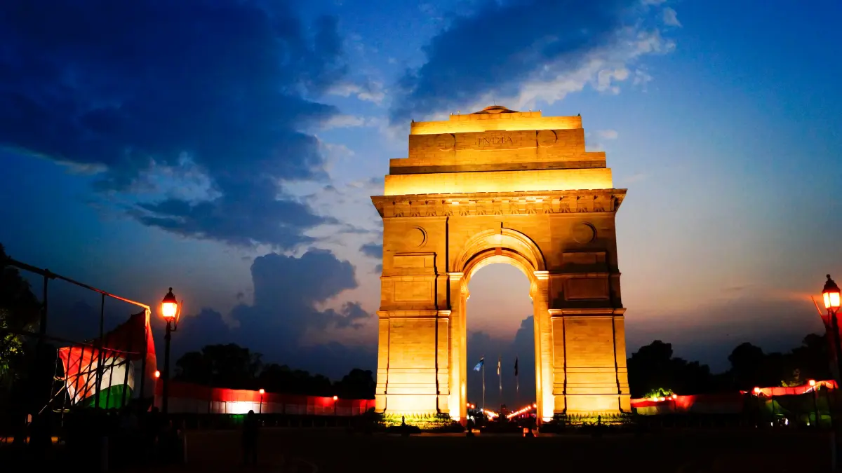 A picture of the war memorial India Gate in New Delhi, India. The archway is carved intricately and is constructed of red sandstone.