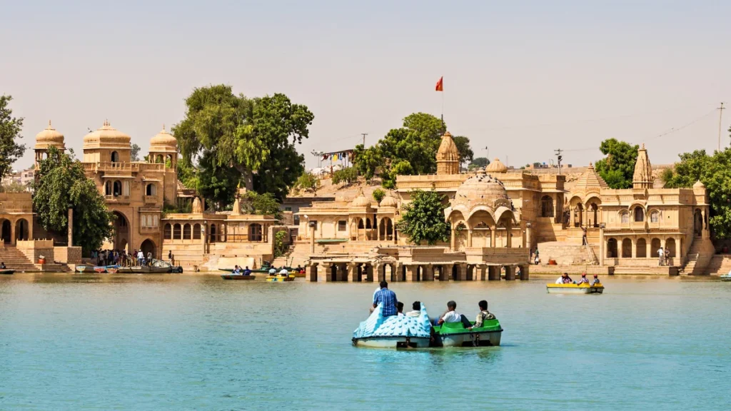 Gadsisar Lake at sunset with ornate temples and surrounding architecture, Jaisalmer